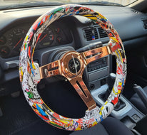 A steering wheel cover featuring a colorful comic book and graffiti print, wrapped around a bronze-colored spoke steering wheel, 